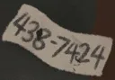 House 2 torn paper scrap dropping from stabbed attic suitcase showing number code